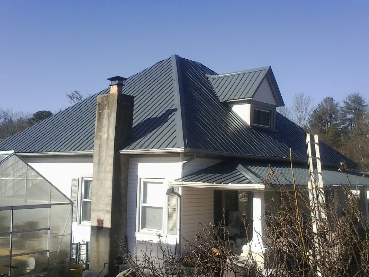 Dark blue standing seam metal roof on a white farmhouse with dormer — Slate & Tile Roof Repair by Roofing Brothers in Milan
