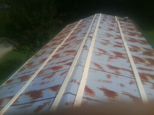 Rusted metal roof panels with new wood purlins before replacement — Storm Damage Roof Repair in Milan by Roofing Brothers
