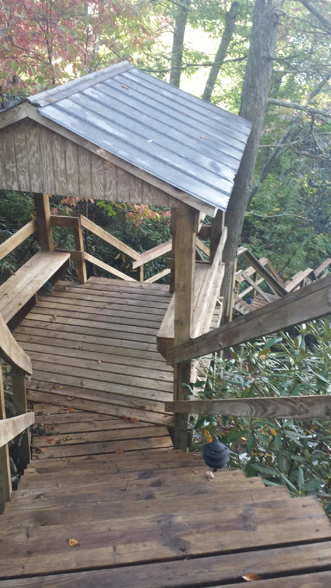 Metal roofed shelter over wooden steps on a wooded walkway — Skylight Repair & Installation work by our crew in Milan