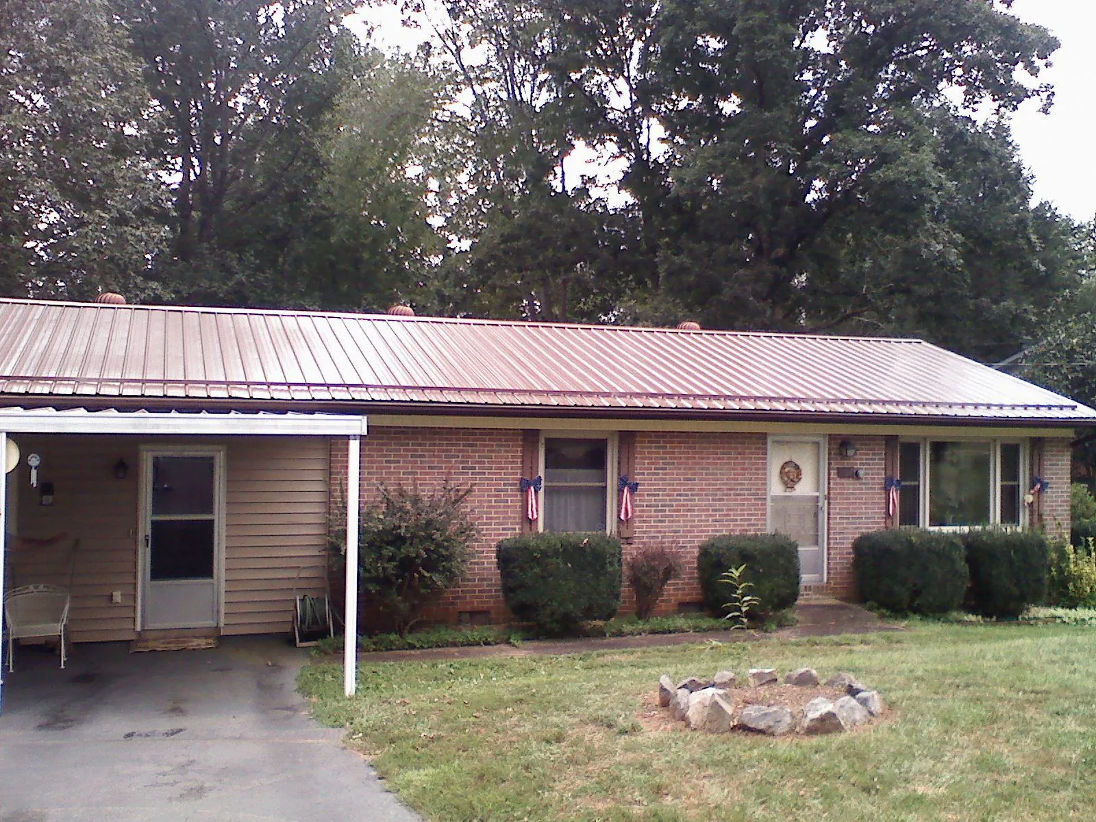 Bronze metal roof and carport on a brick ranch home — Roof Repair work by our crew in Milan