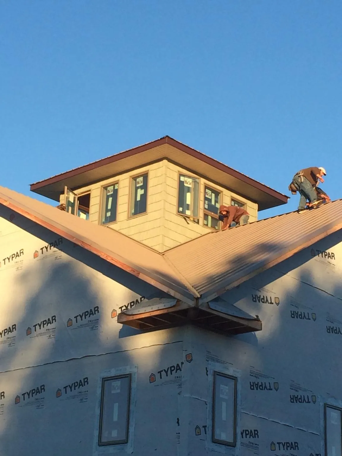Roofers working around a rooftop cupola on a new metal roof at sunset — Roof Waterproofing in Milan by Roofing Brothers